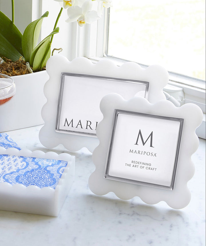 White photo frames with 'MARIPOSA' branding on a marble surface with drinks and flowers.